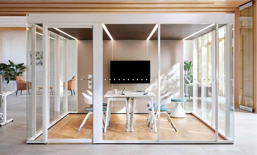 Modern office space with glass partition walls and a conference table.